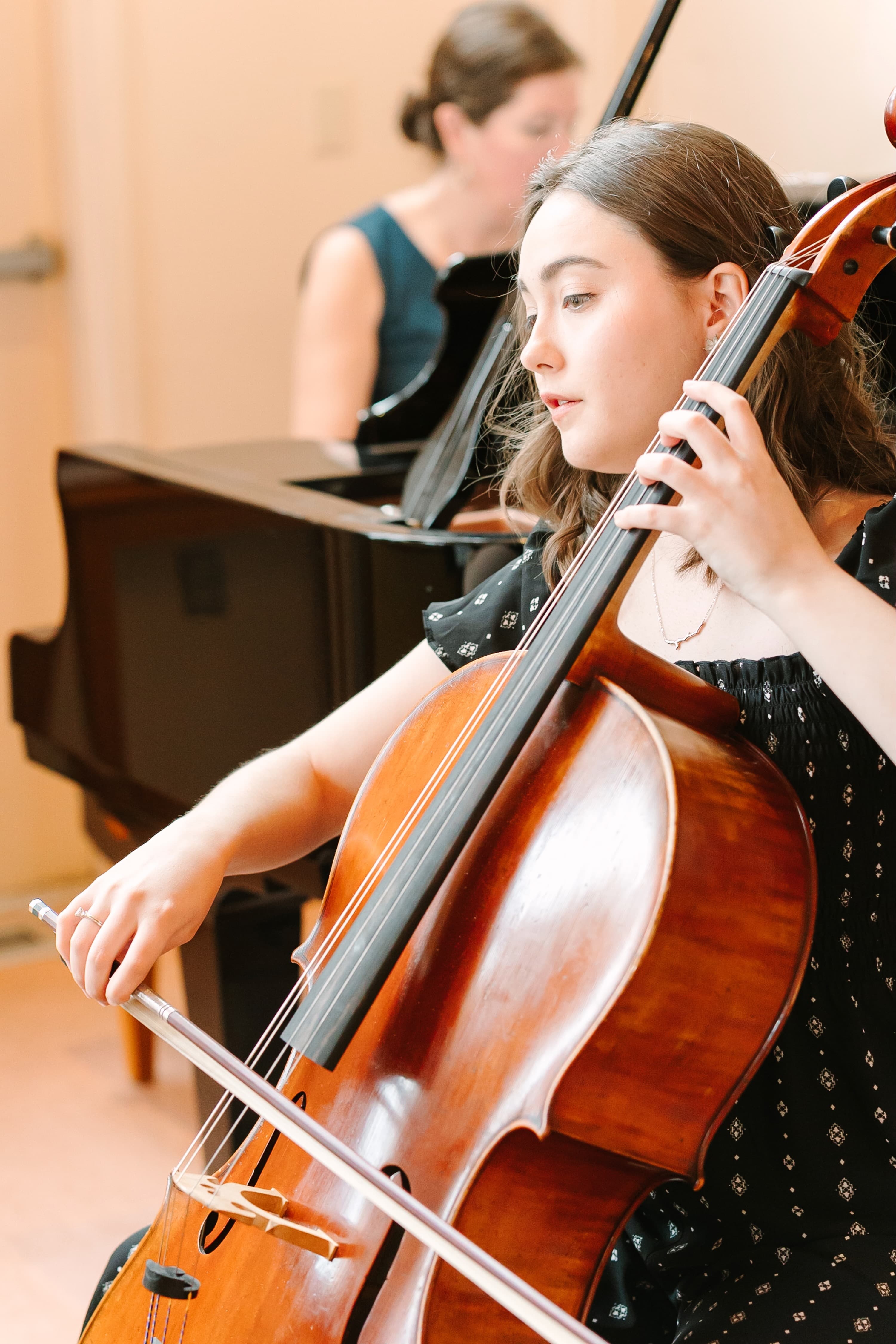 Close-up of a cellist mid-performance beside a pianist