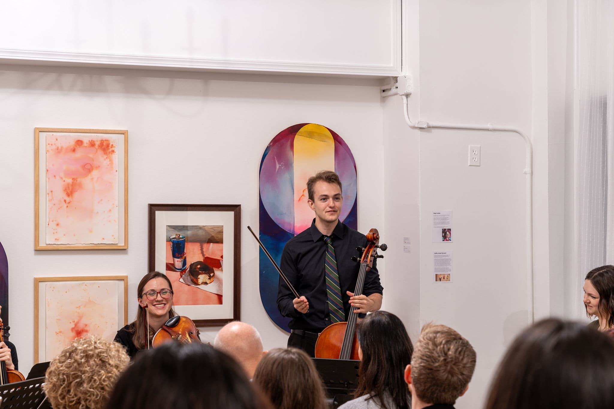 Cellist and violist performing for an audience in an art gallery